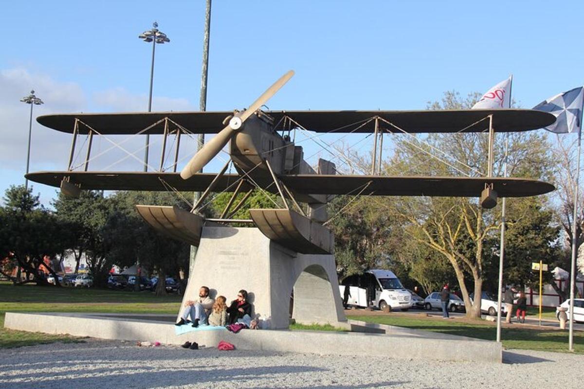 Un grupo de personas sentadas bajo una estatua de un avión.