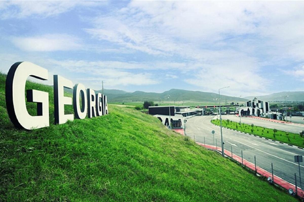 un cartello in cima a una collina erbosa con un'autostrada