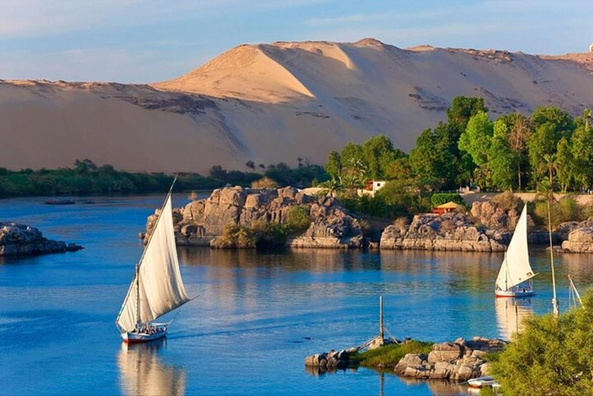 three boats on a river with mountains in the background