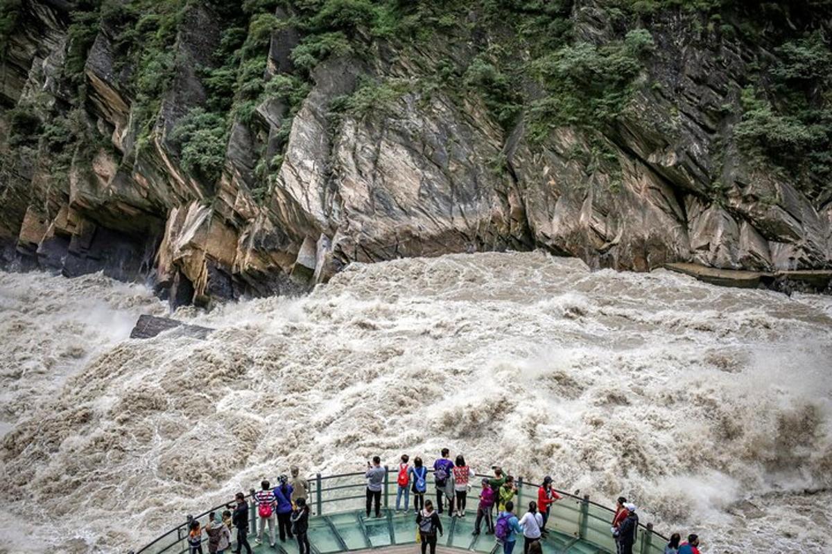 a group of people standing on a bridge near a river