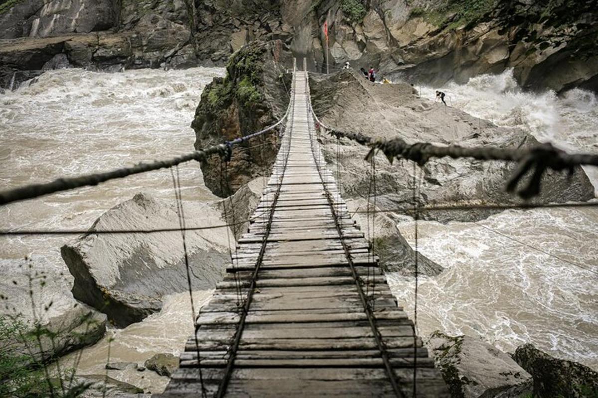 a wooden suspension bridge over a river with waves