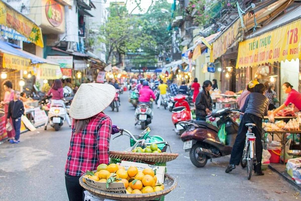 a woman with a hat walking down a street with baskets of oranges