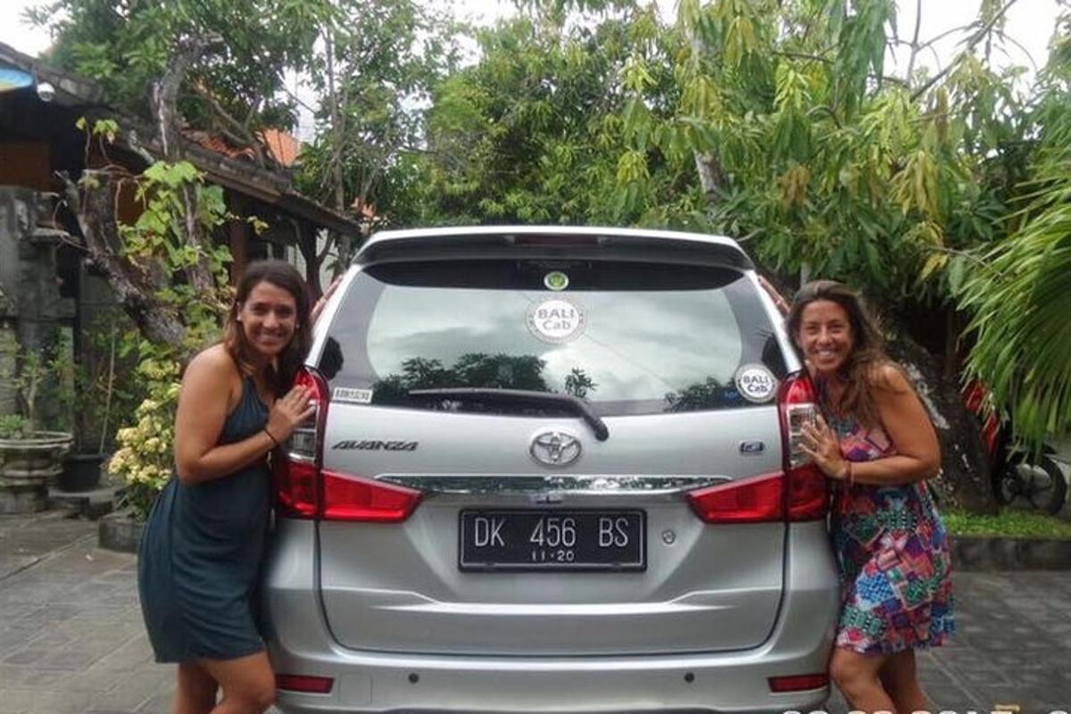 two women standing in front of a car