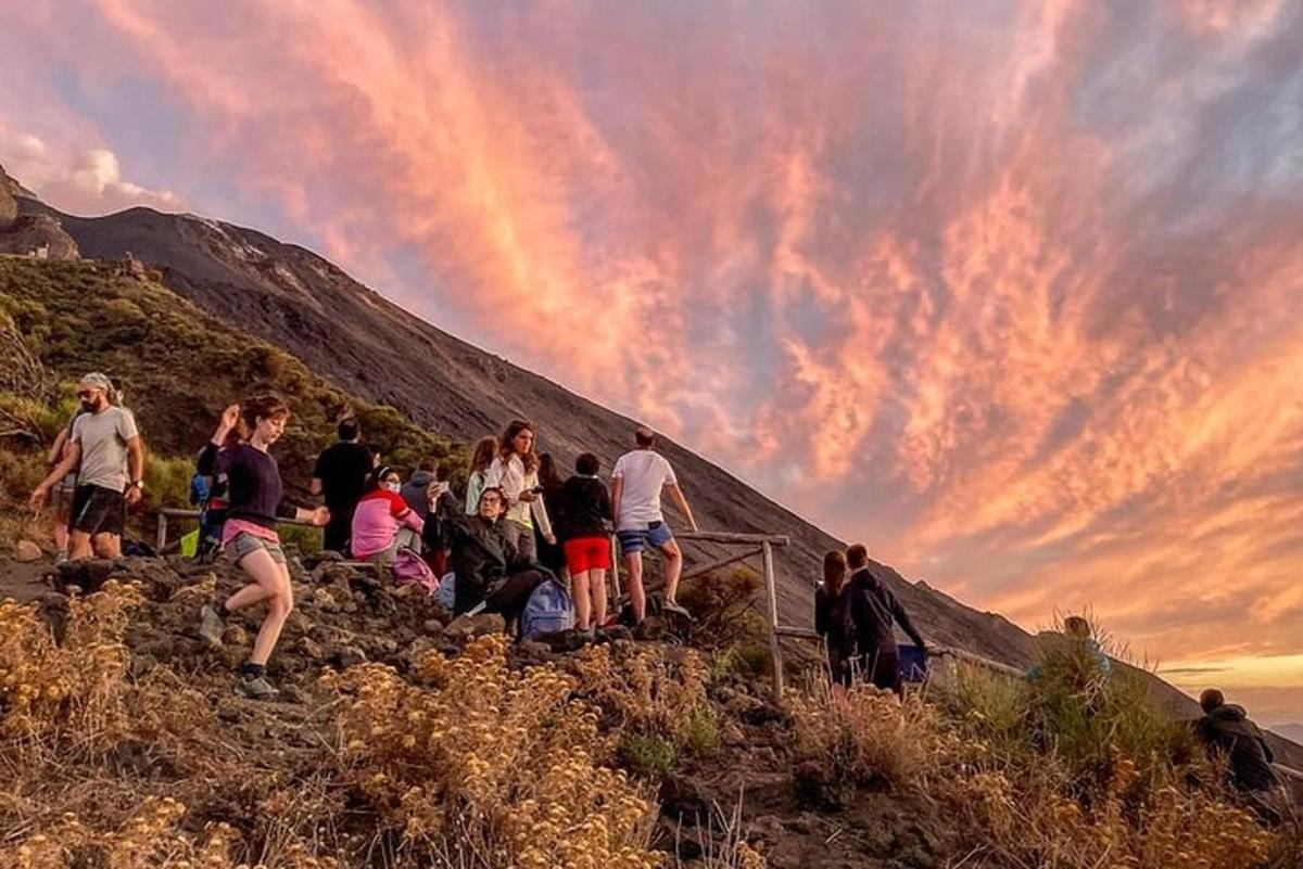 a group of people standing on a hill at sunset