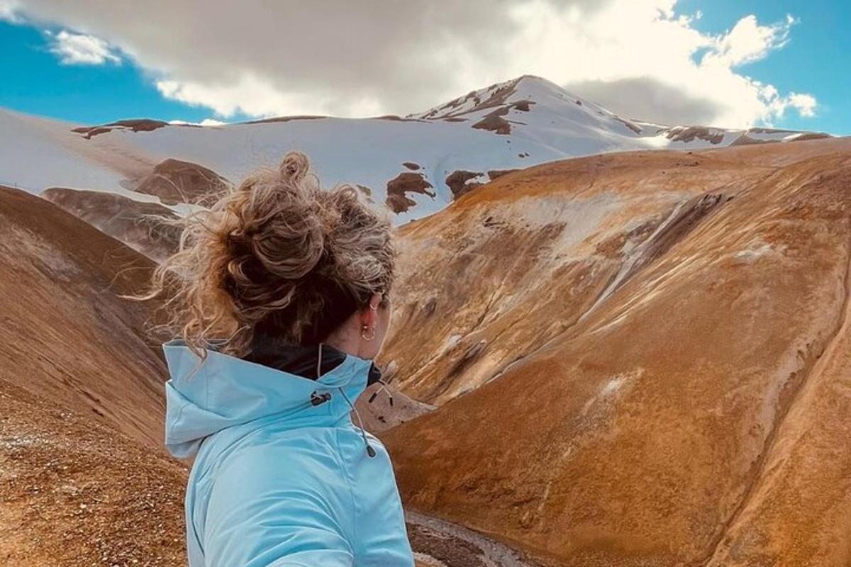 seorang wanita berjaket biru melihat gunung