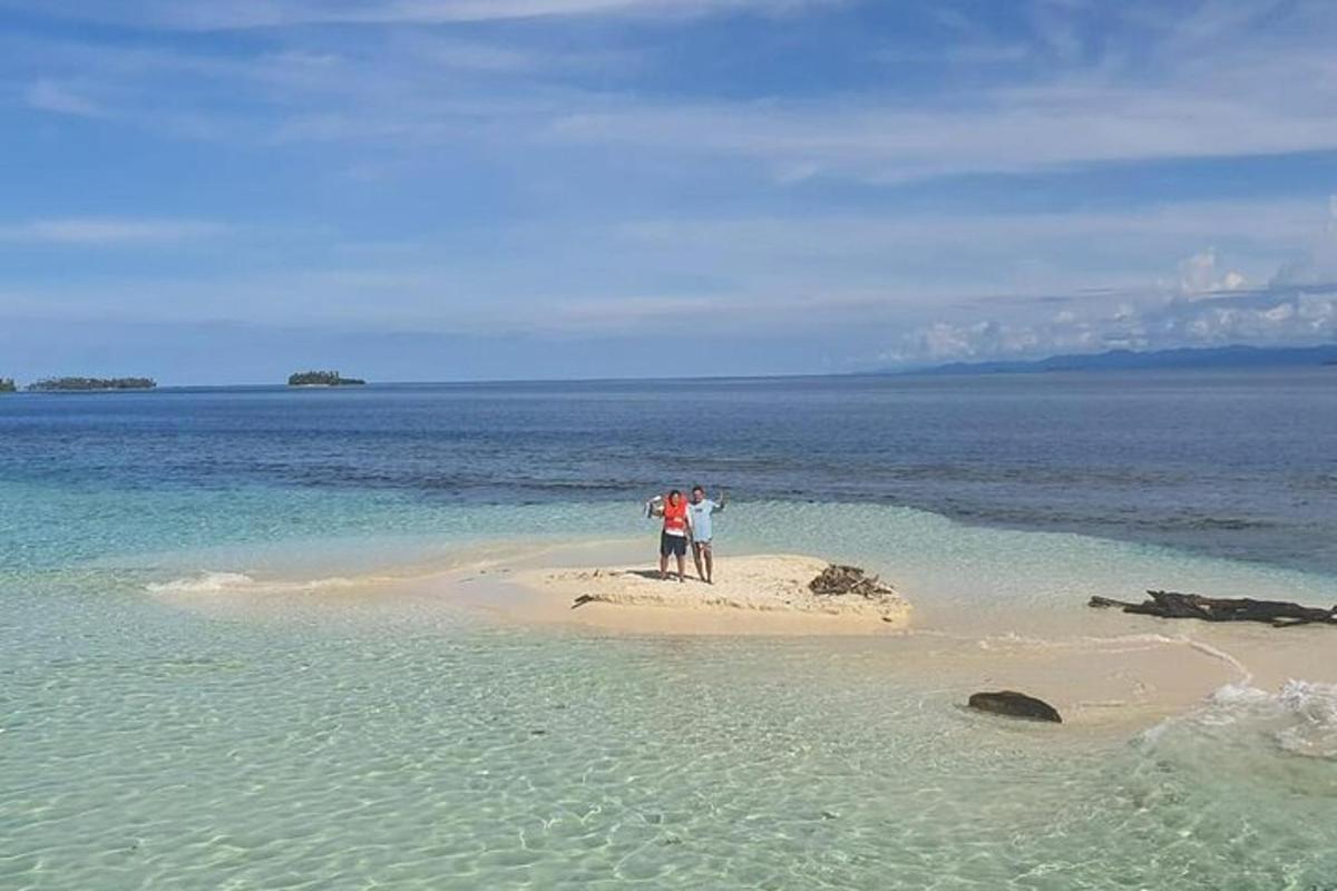 duas pessoas em pé em uma pequena ilha no oceano