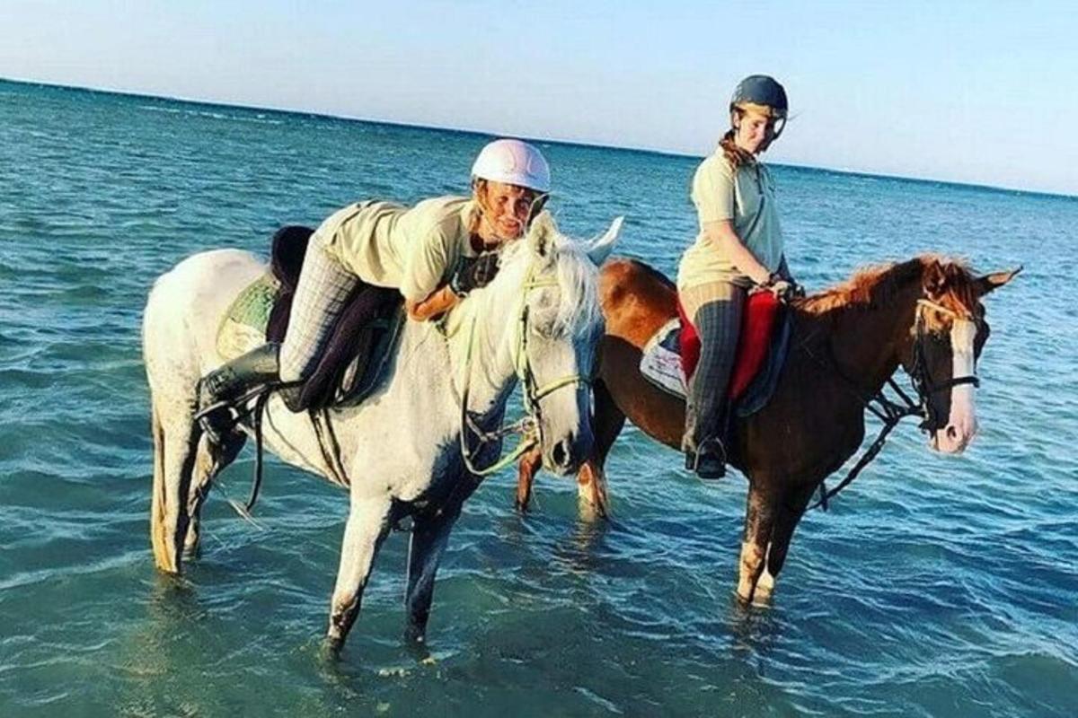 moški in ženska jahata konje v vodi