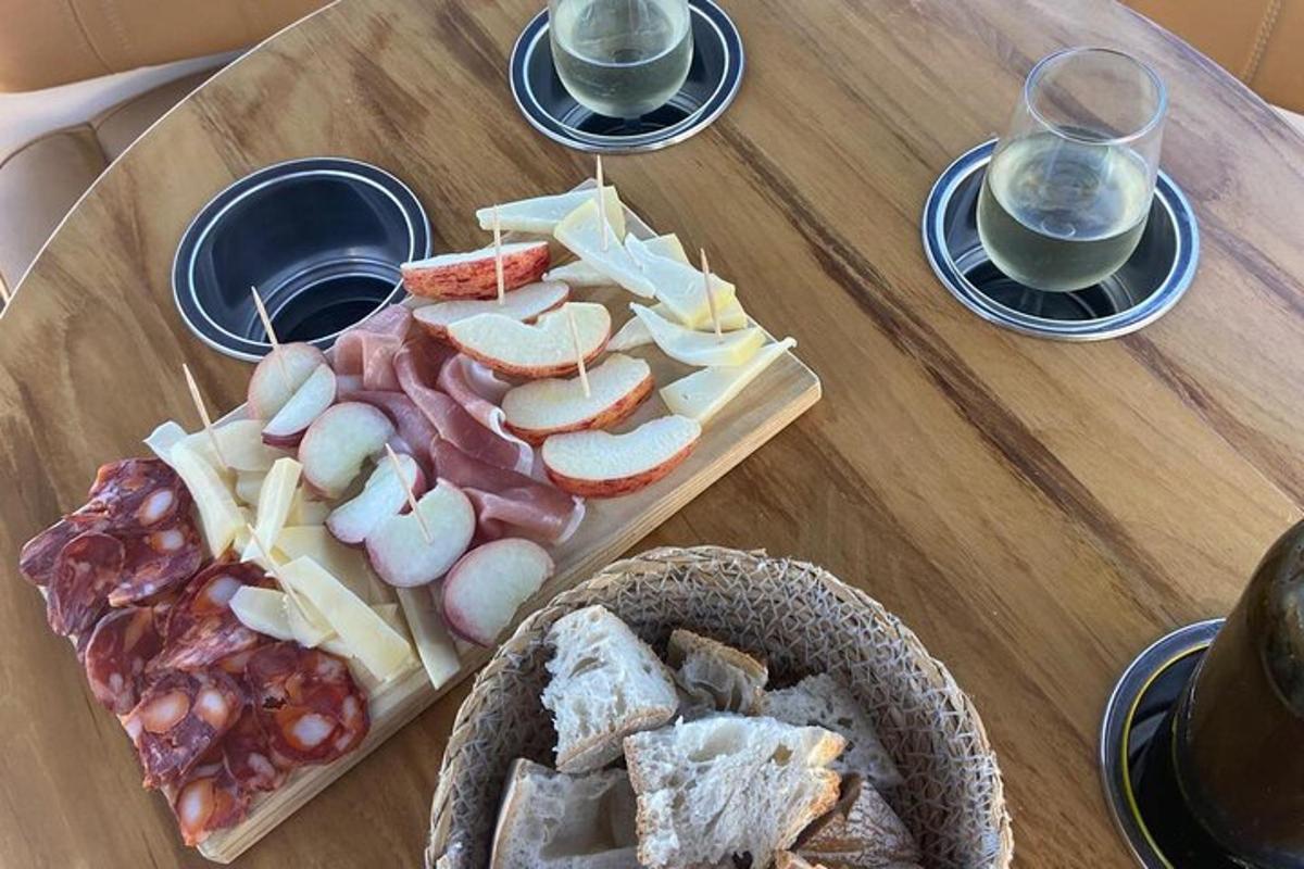 a wooden table with cheese and bread and two glasses of wine