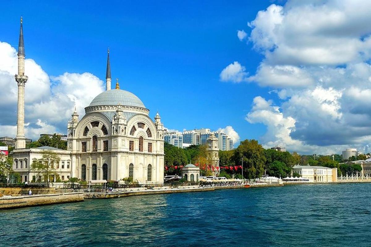 a large building with a mosque in front of the water