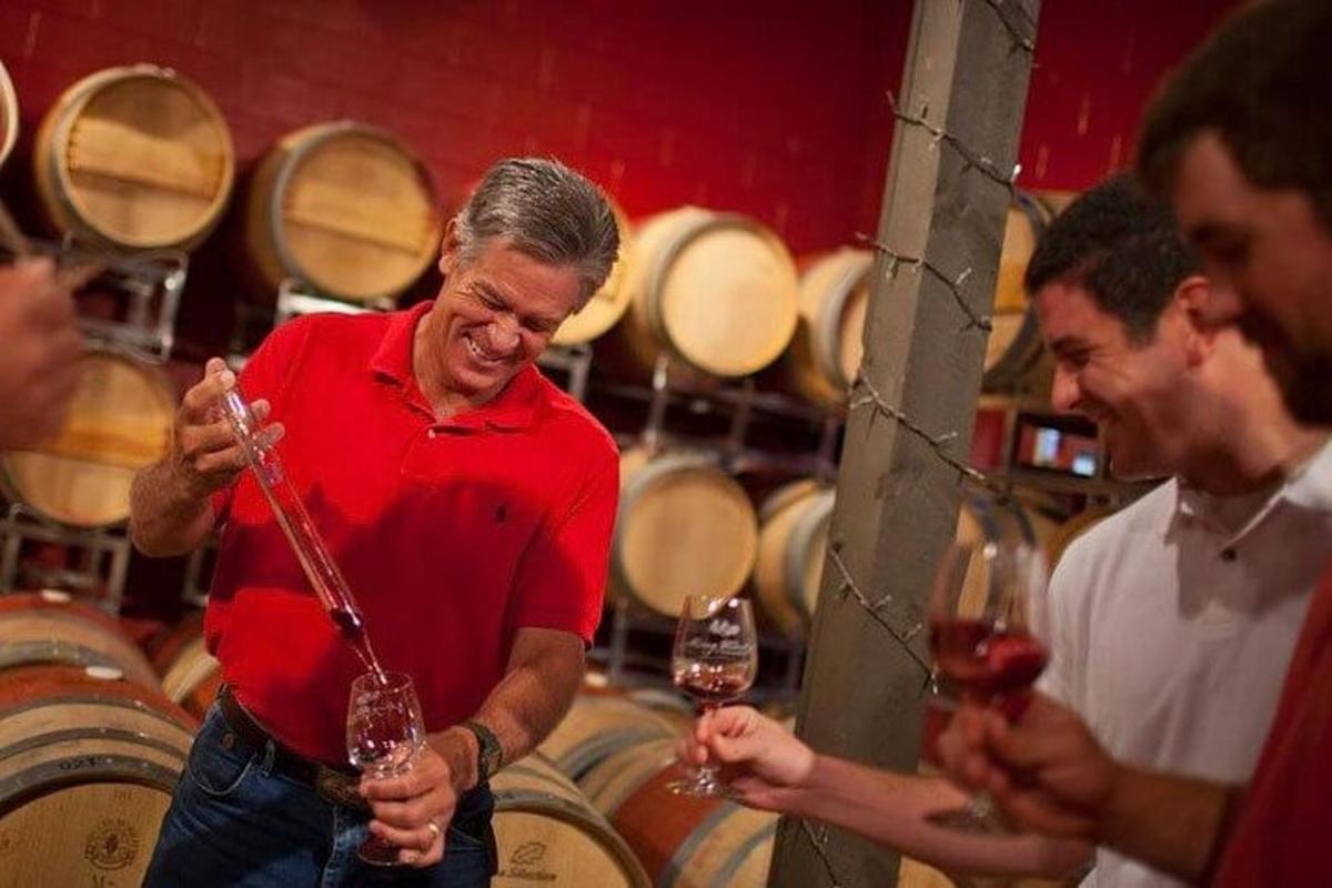 a man holding a glass of wine in a barrel