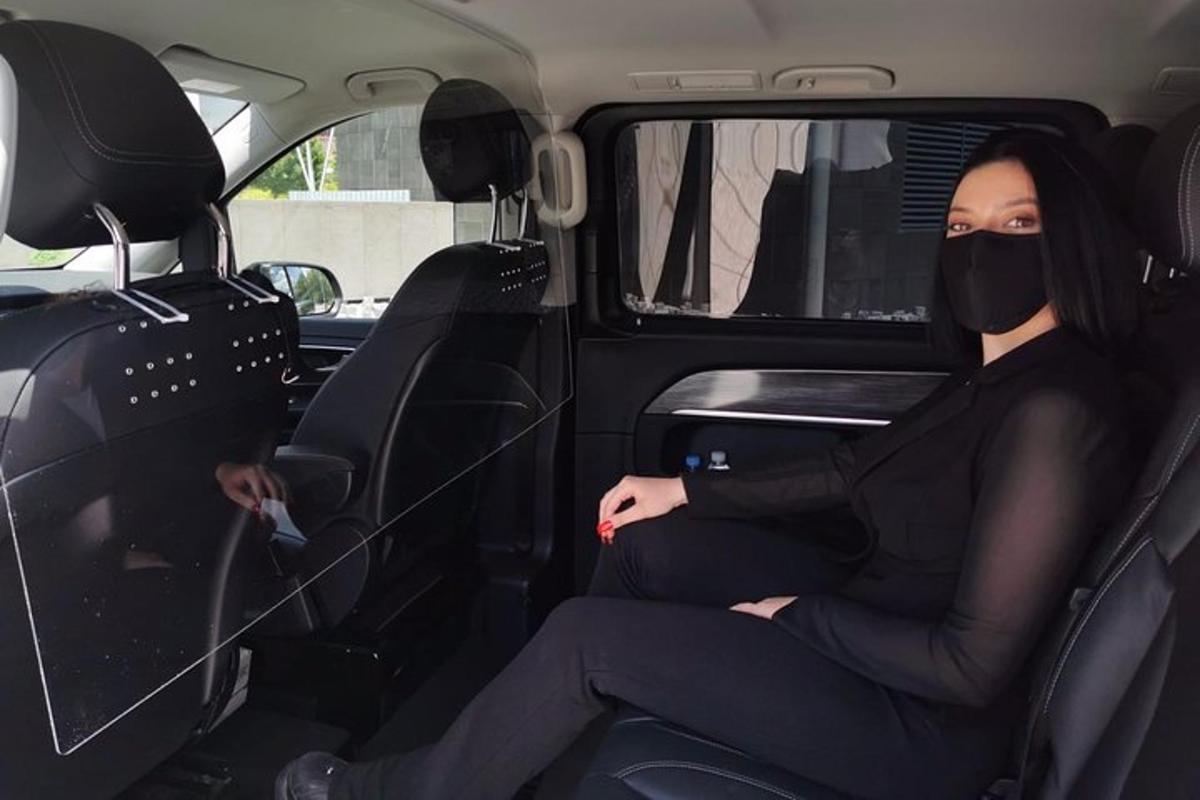 una donna seduta sul sedile posteriore di un'auto che indossa una maschera antigas