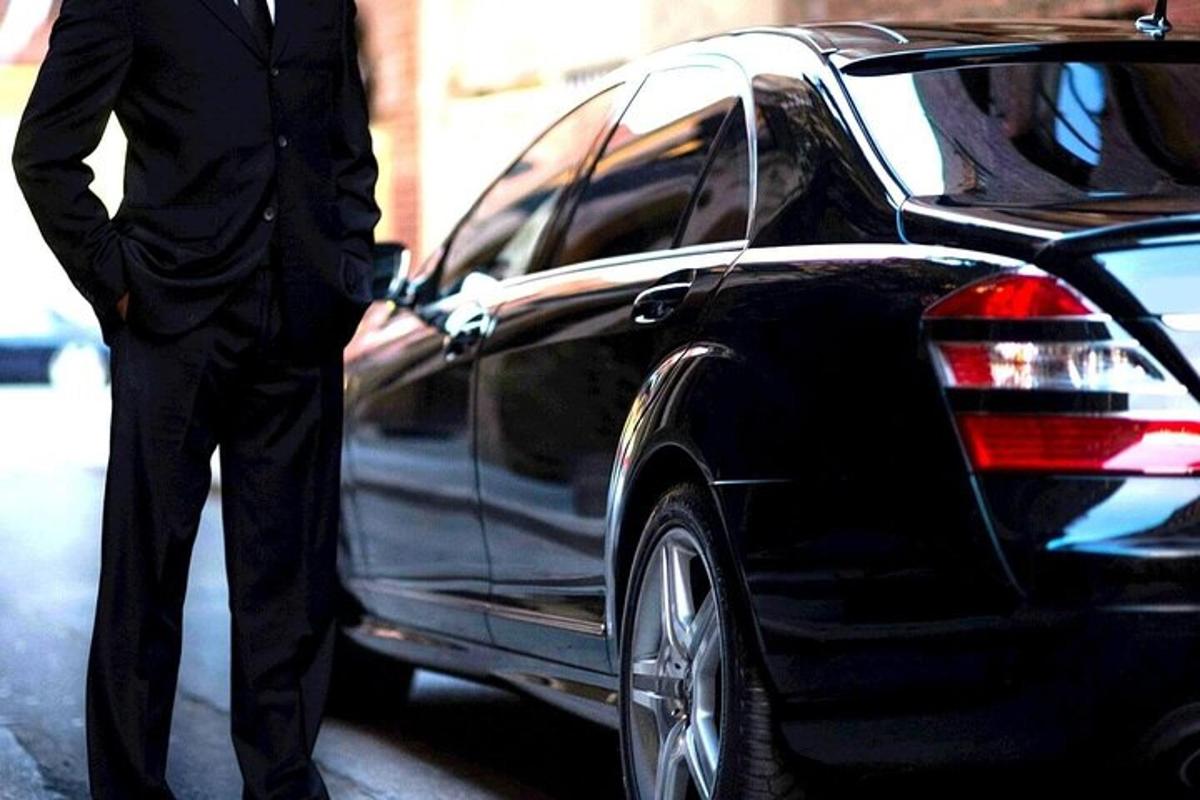 um homem de terno parado ao lado de um carro