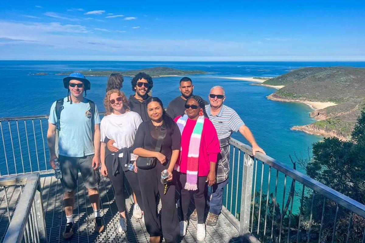 a group of people posing for a picture on a walkway near the ocean