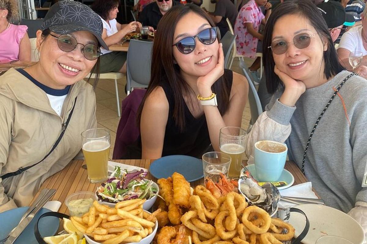 tiga wanita duduk di meja dengan sepinggan makanan