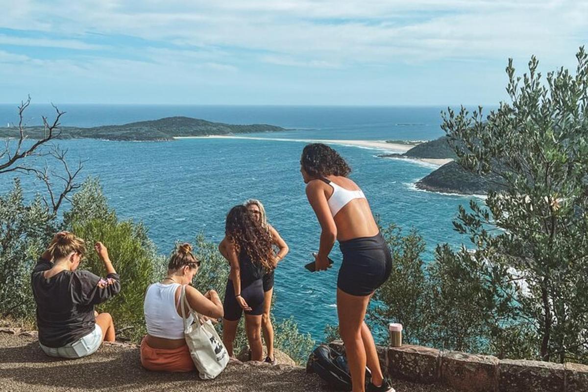 um grupo de mulheres sentadas em uma colina olhando para o oceano