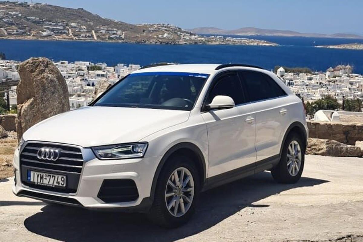Un Audi SUV blanco estacionado frente a un centro comercial.