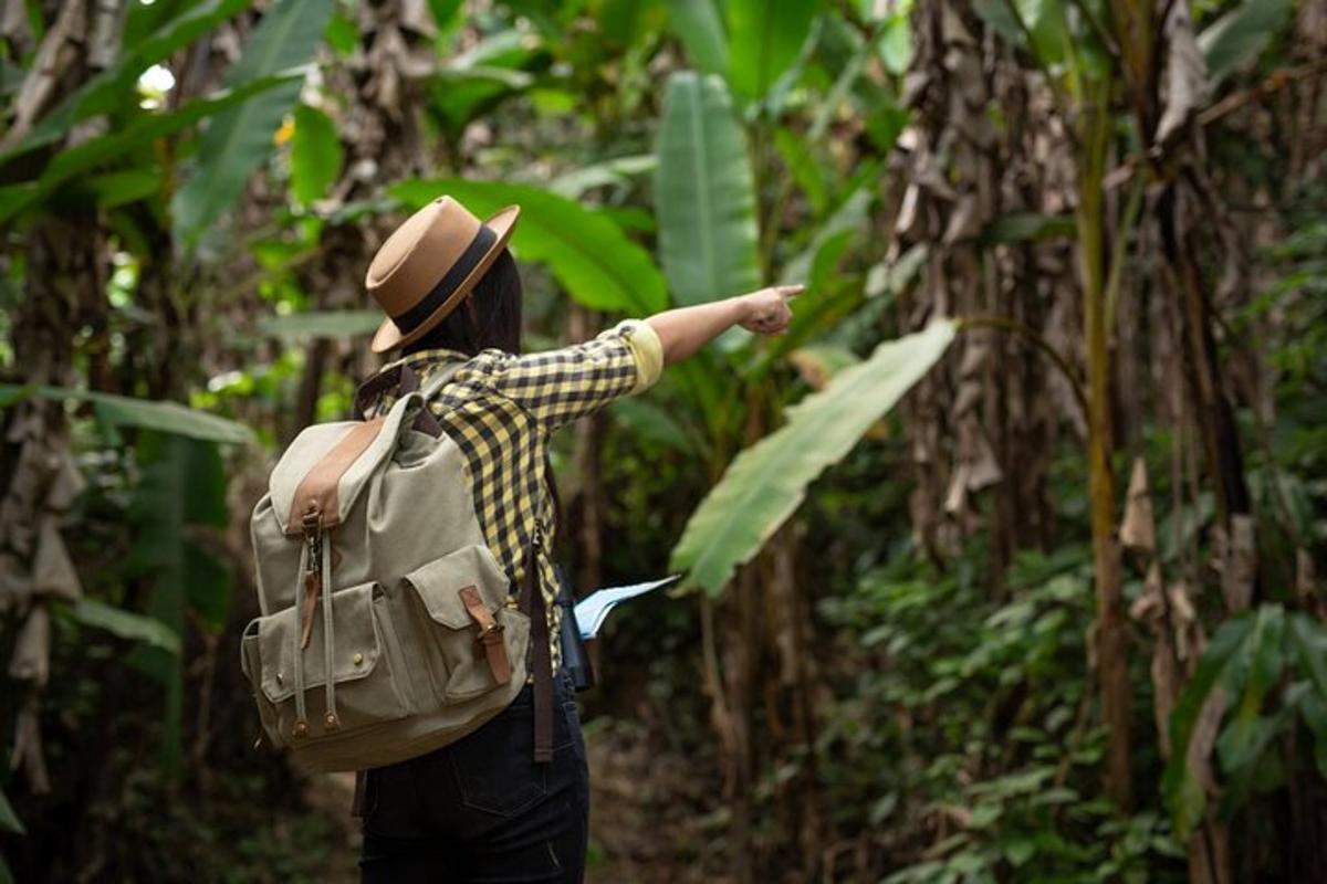 Un hombre con una mochila apuntando hacia la jungla.