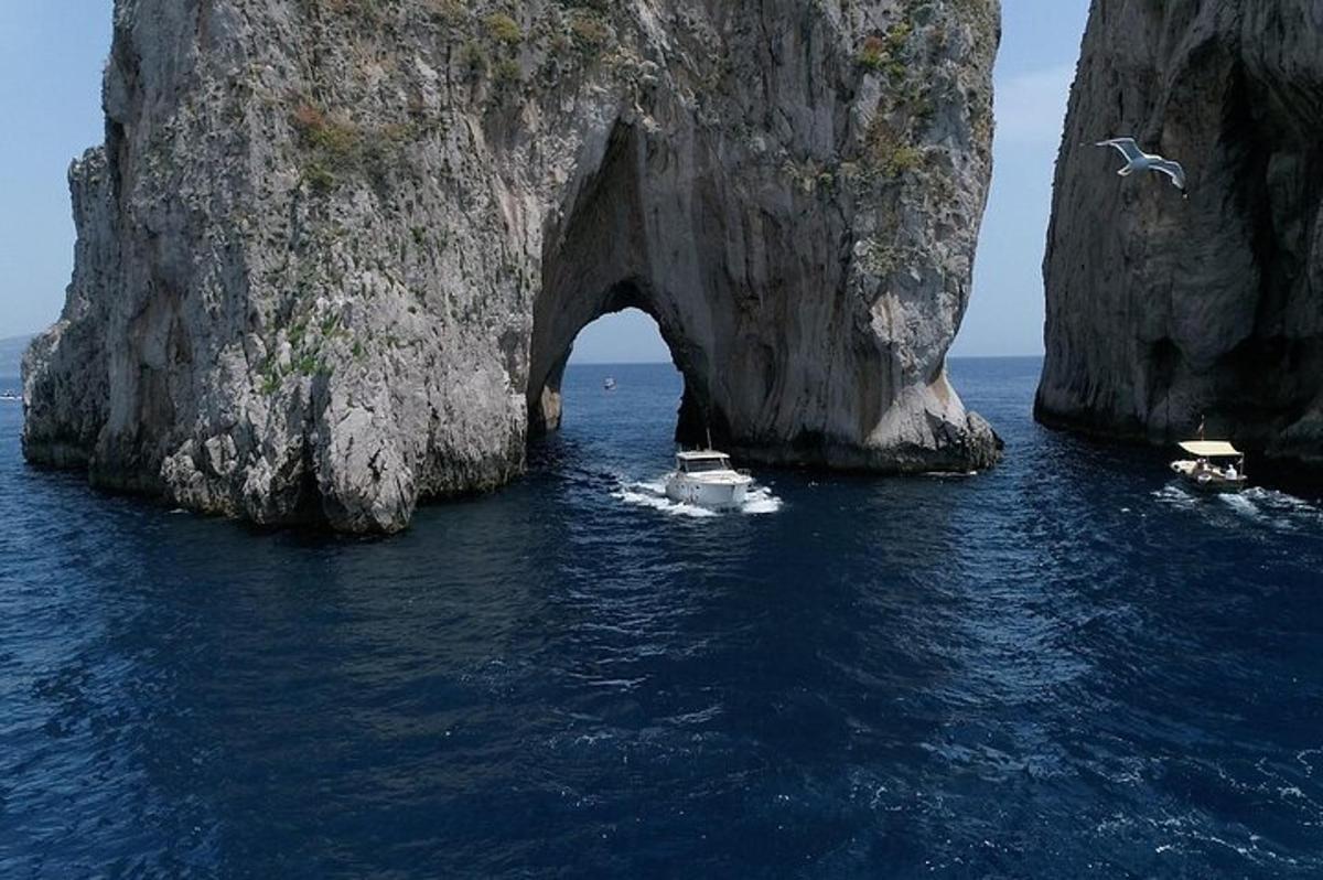 un gruppo di barche in acqua vicino a una grande formazione rocciosa