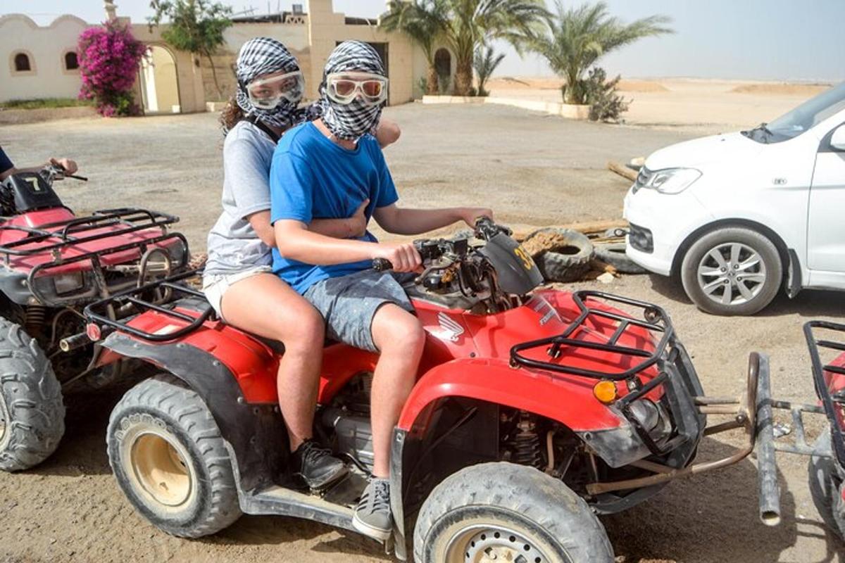 duas pessoas em um quadriciclo no deserto