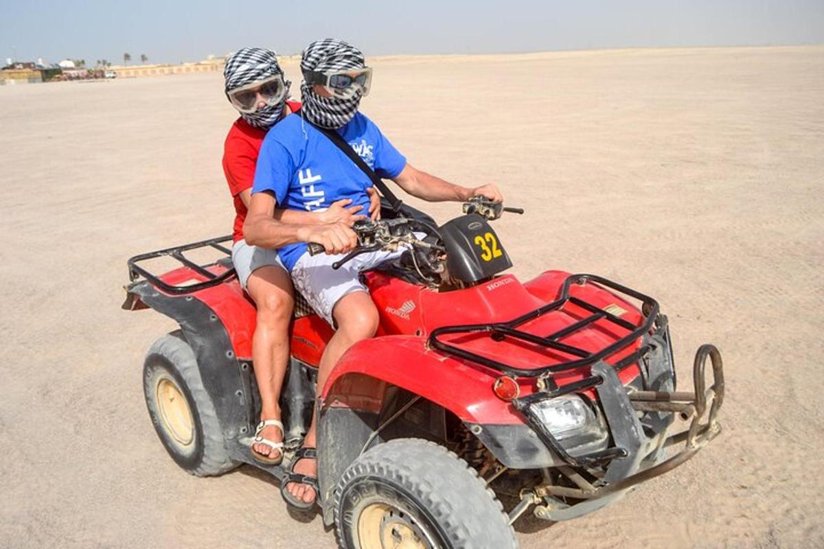 duas pessoas andando de quadriciclo na praia