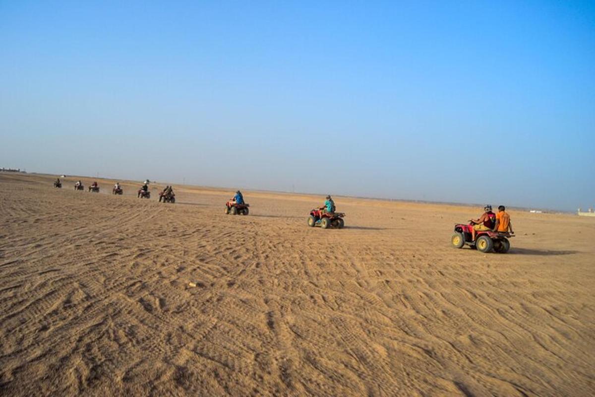 um grupo de pessoas andando de quadriciclo no deserto