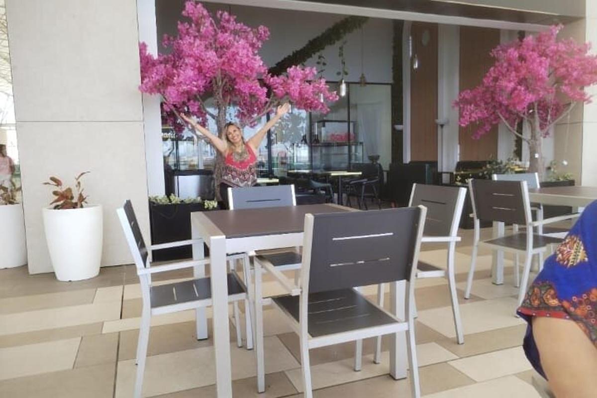 Μια γυναίκα στέκεται μπροστά σε ένα τραπέζι με ροζ λουλούδια