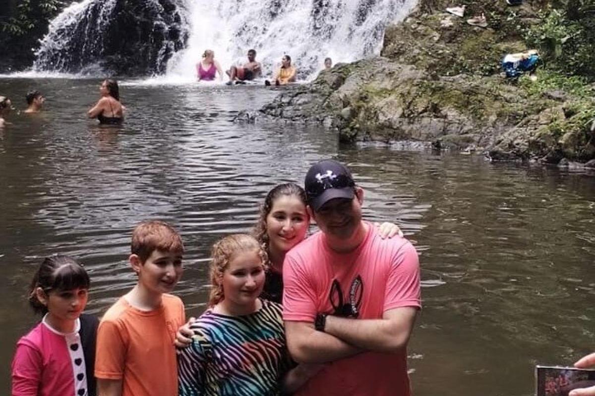 un uomo e la sua famiglia in piedi davanti a una cascata