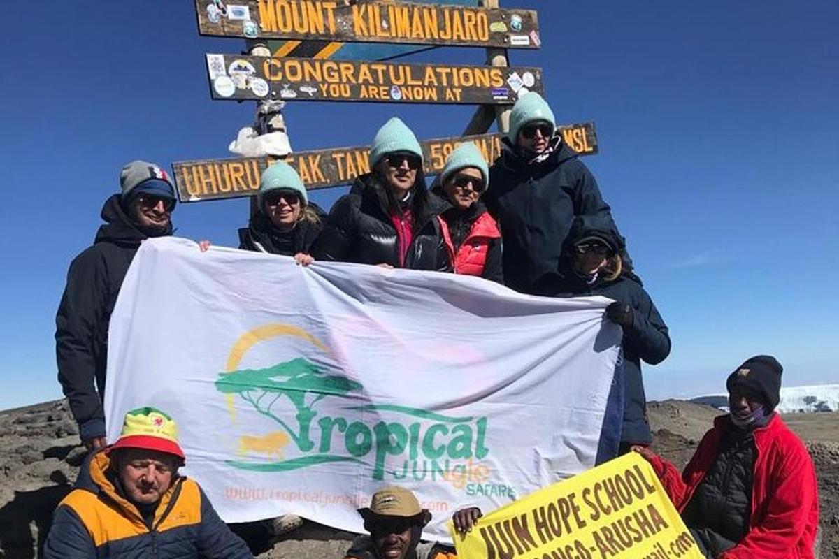 un gruppo di persone che tengono un cartello in cima a una montagna