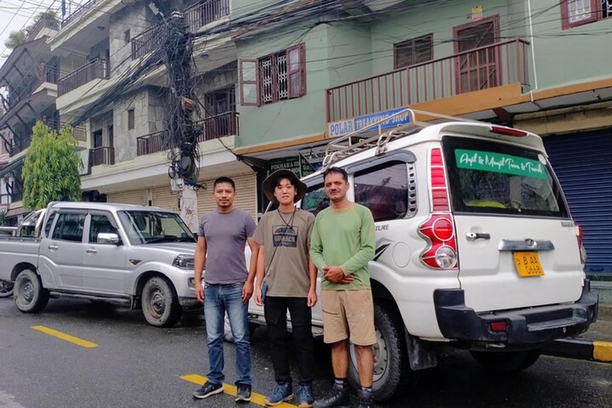 a group of three men standing next to a white van