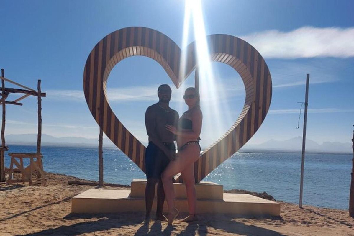 um homem e uma mulher em pé em frente a uma estátua de coração