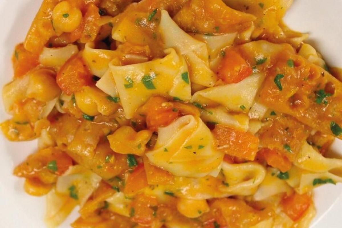 a white plate of pasta with carrots and potatoes