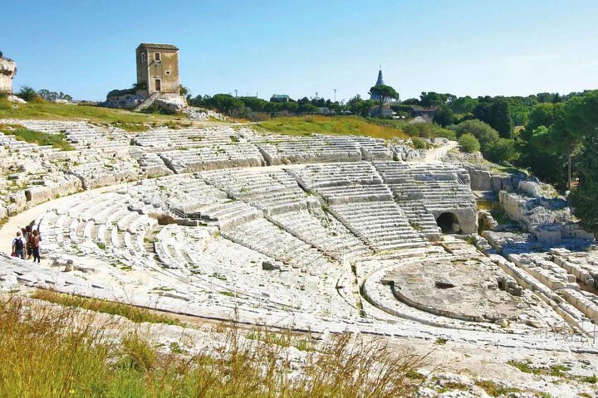 an ancient amphitheater with a building in the background
