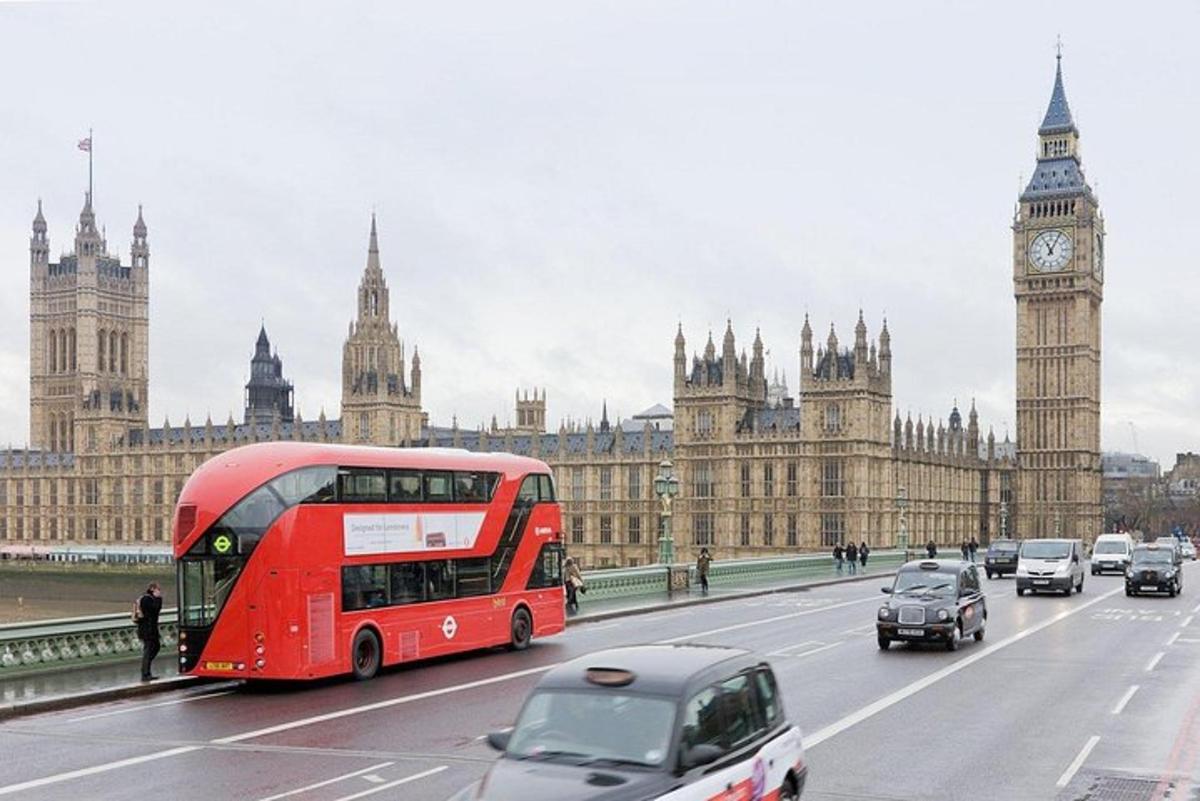 a red double decker bus driving past the big ben clock tower