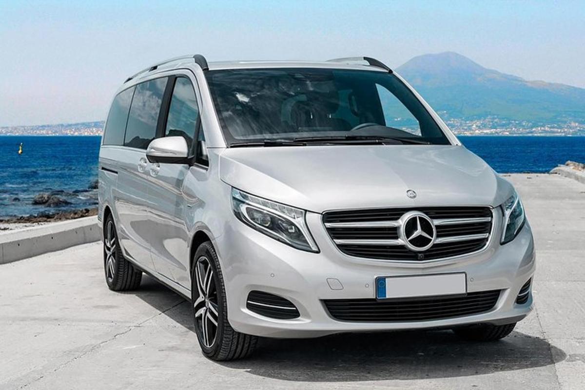 Bílá dodávka Mercedes Benz zaparkovaná u oceánu