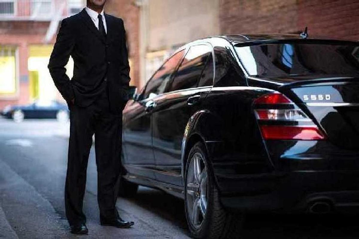 ένας άντρας με κοστούμι που στέκεται δίπλα σε ένα αυτοκίνητο