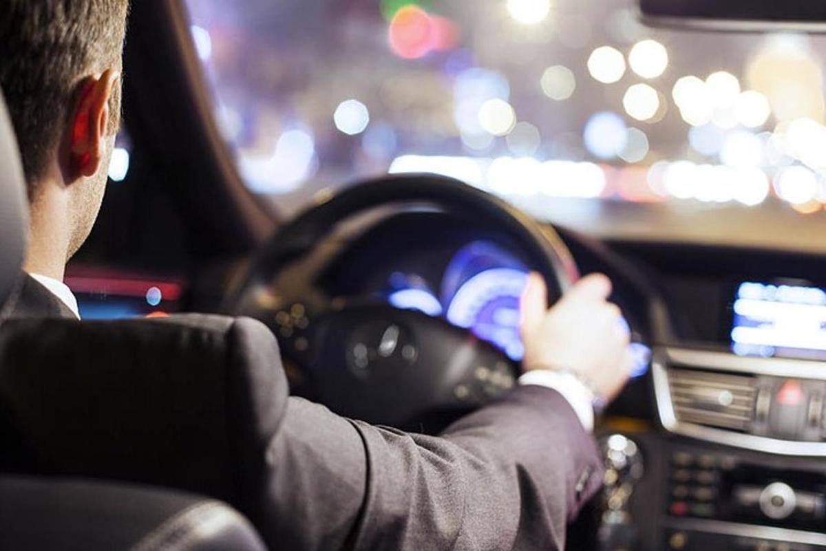 een man in een pak die een auto bestuurt