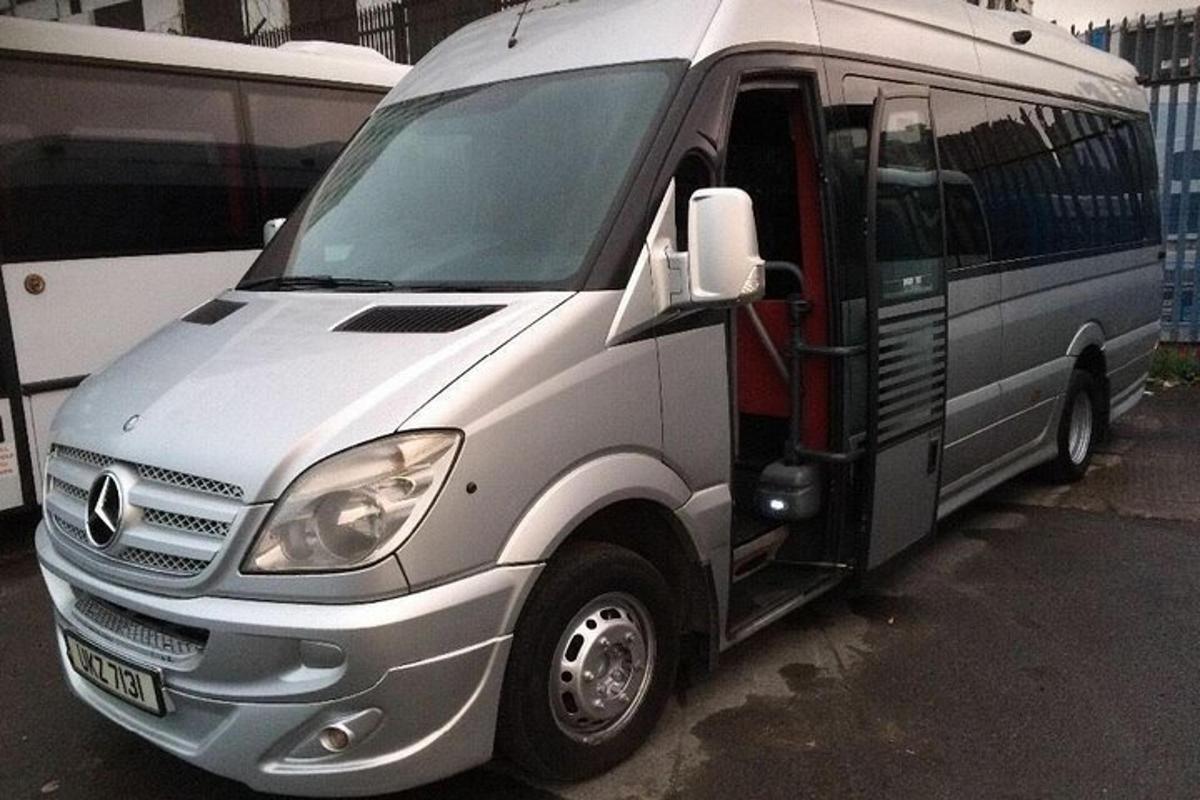 una furgoneta platejada aparcada al costat d'un autobús