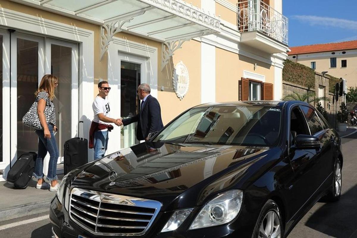 grupė žmonių, stovinčių prie juodo automobilio