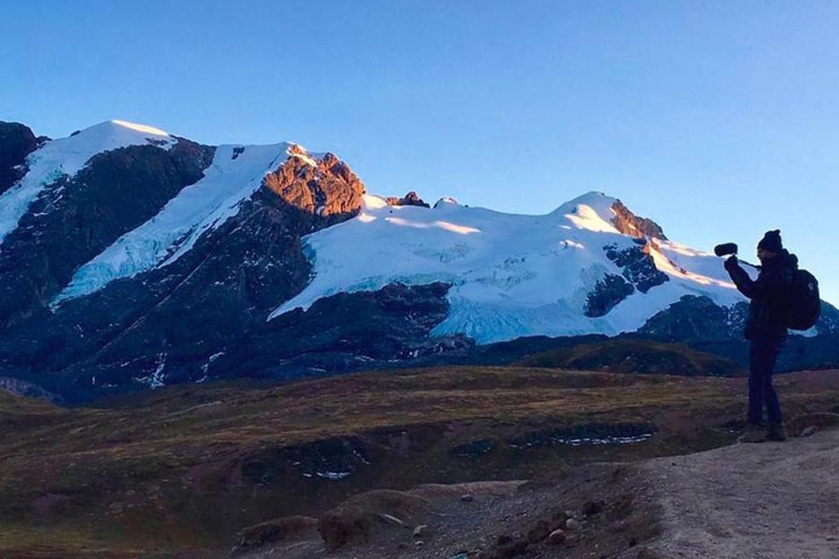 um homem tirando uma foto de uma montanha coberta de neve