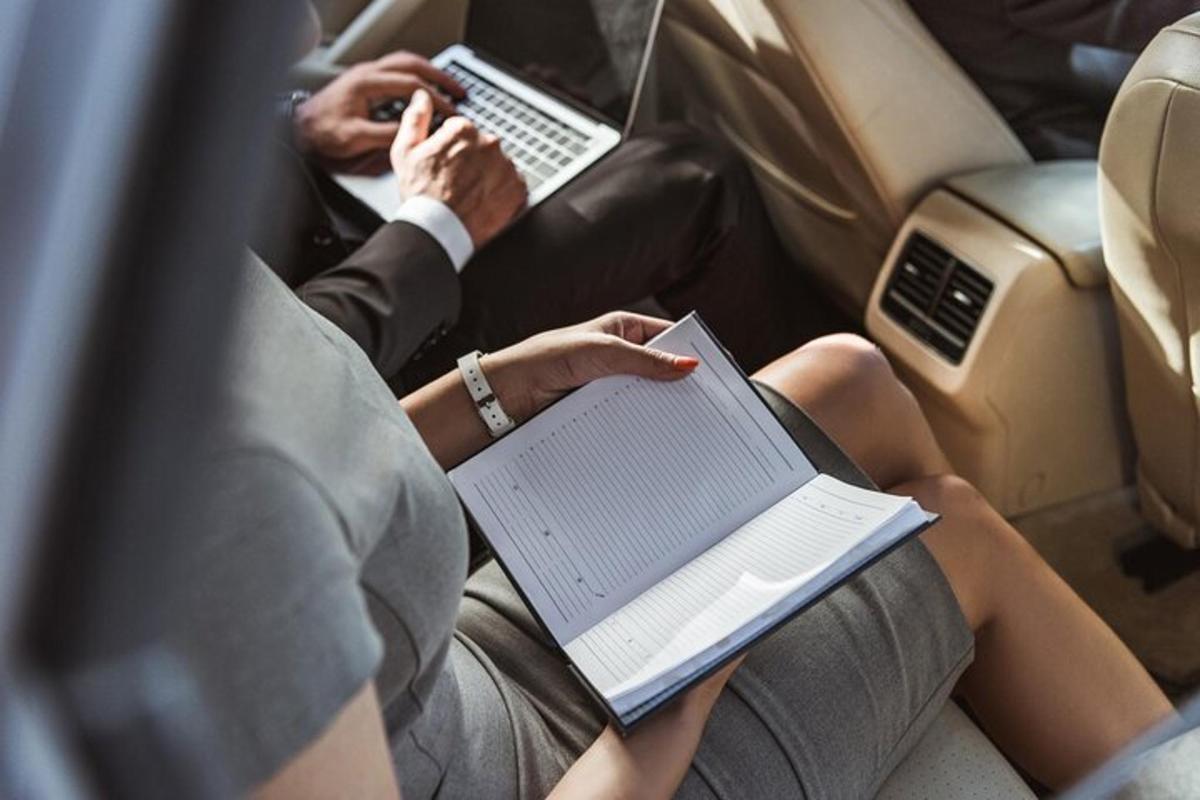 o femeie stând într-o mașină cu o carte și un laptop