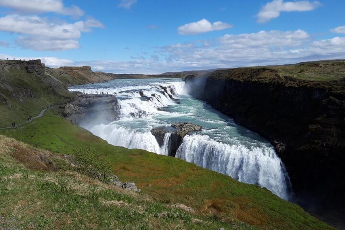 a waterfall on the side of a river in a field