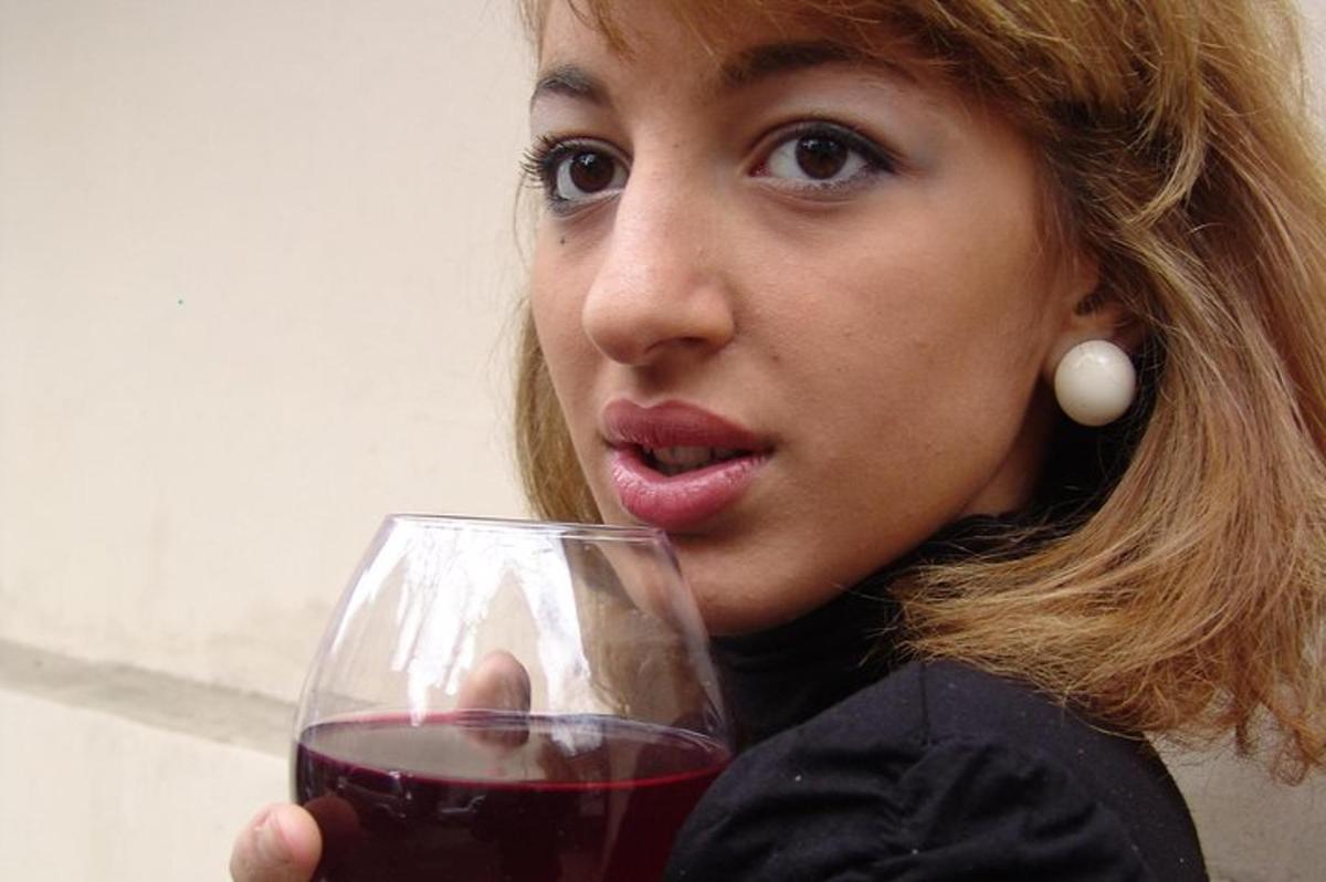 μια γυναίκα που κρατάει ένα ποτήρι κόκκινο κρασί