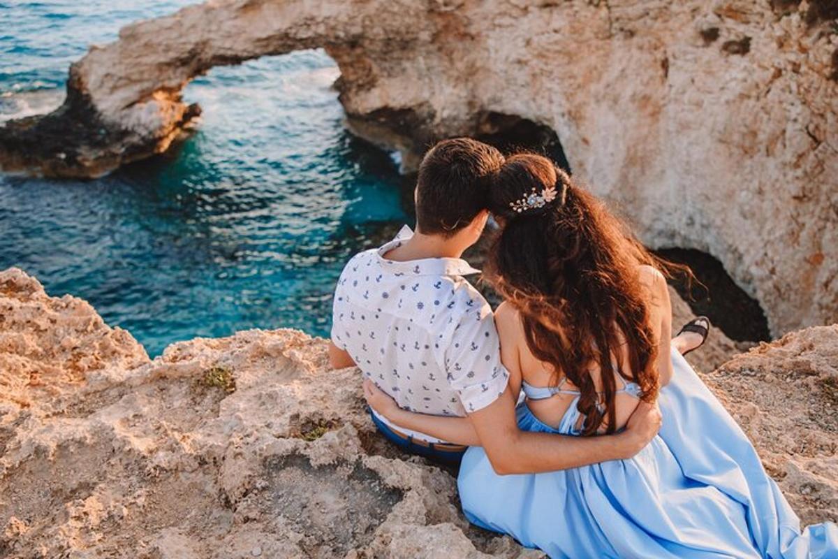 um casal sentado em pedras perto da água