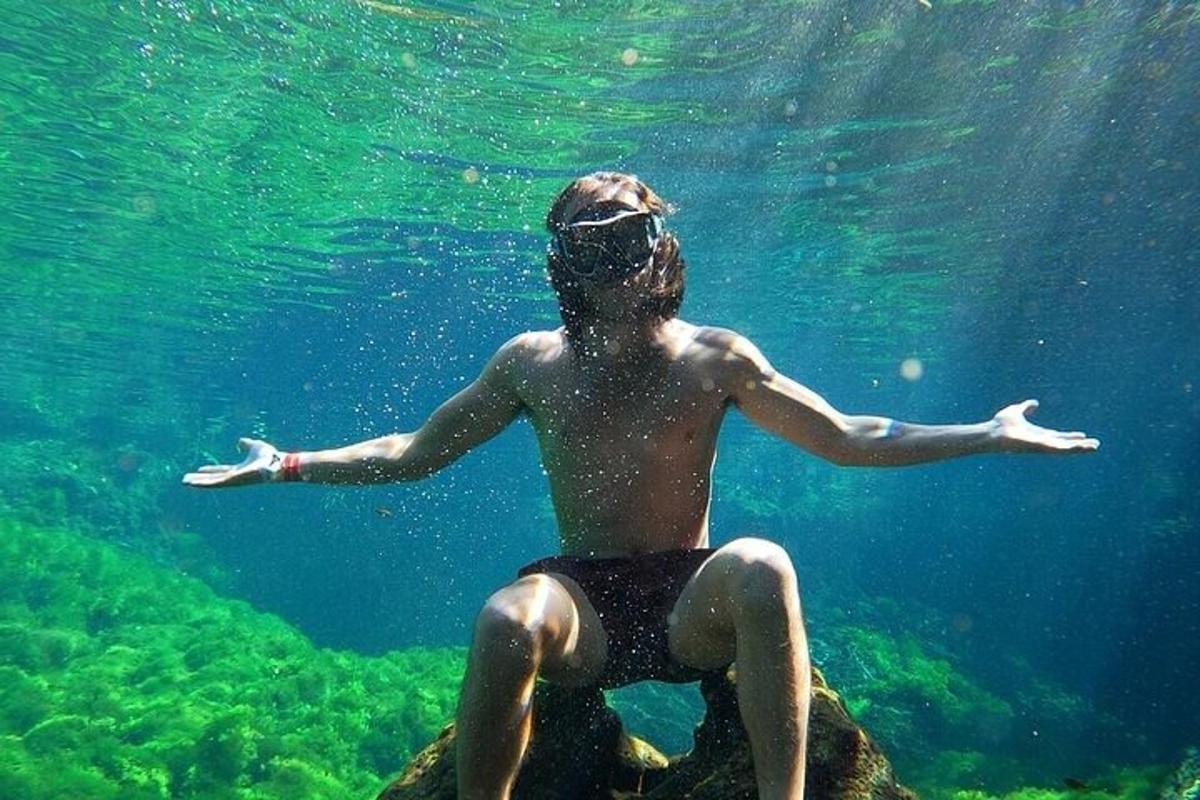 un hombre sentado en una roca bajo el agua