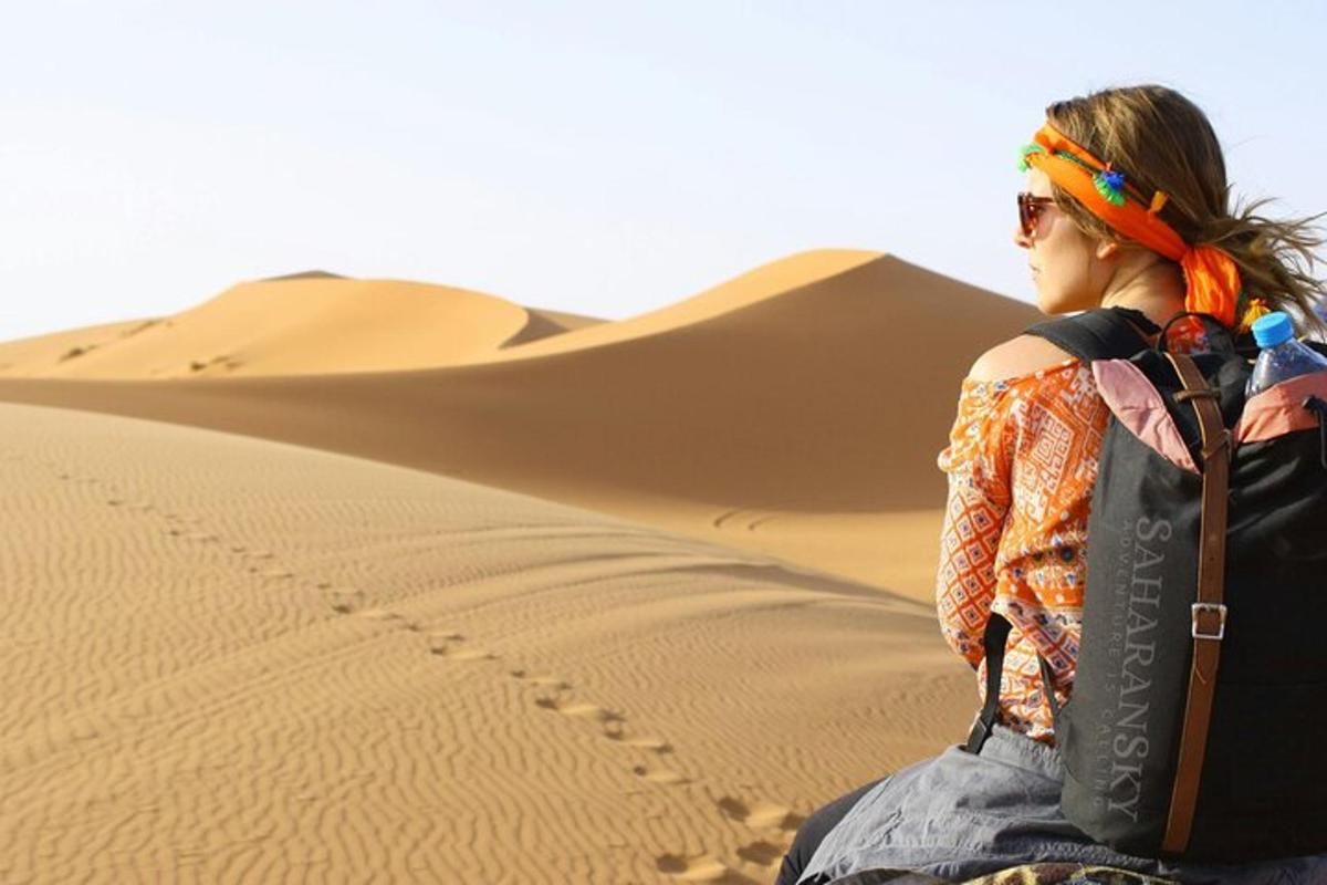 امرأة تجلس في الصحراء وتحمل حقيبة ظهر