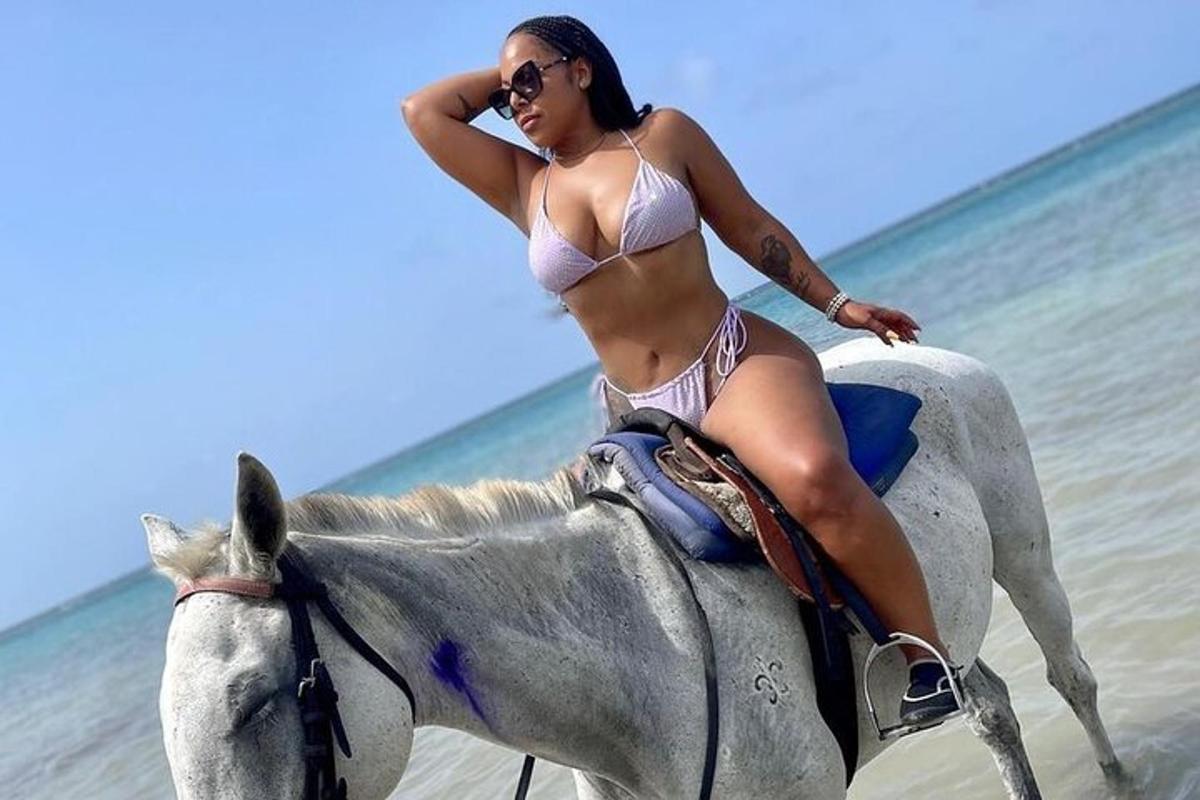 una donna in bikini a cavallo sulla spiaggia