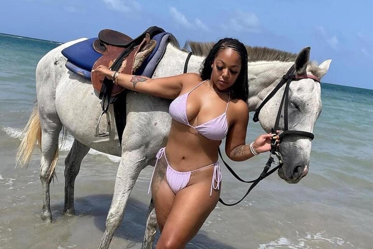 una donna in bikini in piedi accanto a un cavallo sulla spiaggia