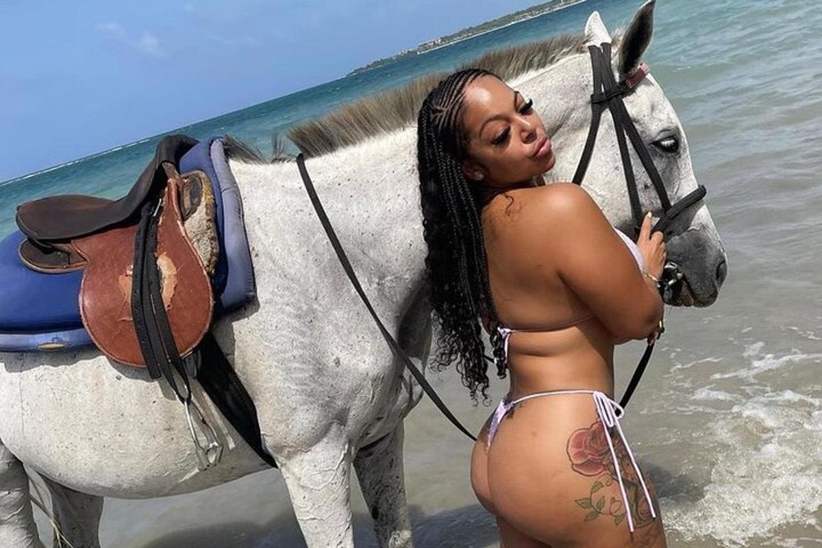 una donna in bikini in piedi accanto a un cavallo sulla spiaggia
