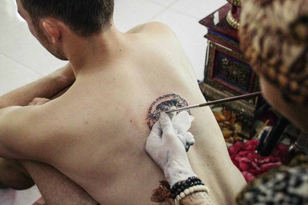 un uomo a torso nudo che si fa un tatuaggio sulla schiena
