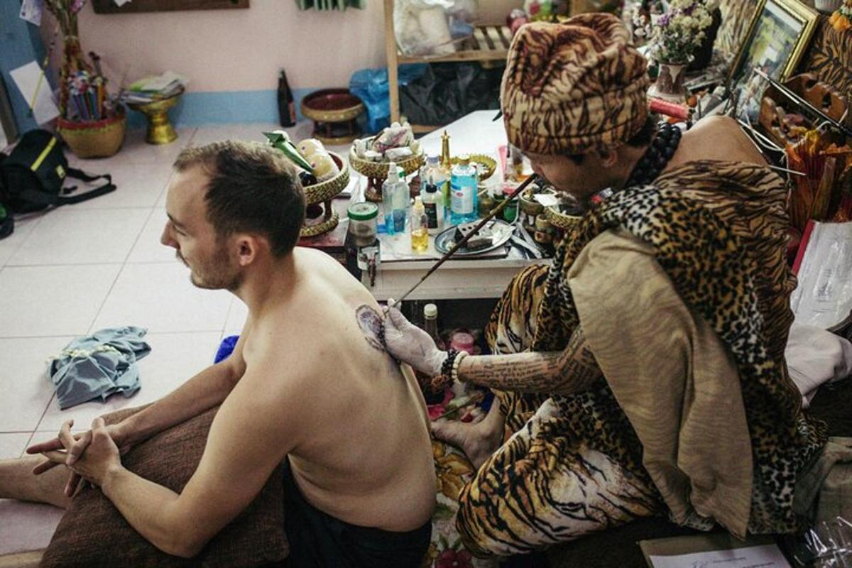 muž bez trička si nechává tetovat na paži muže